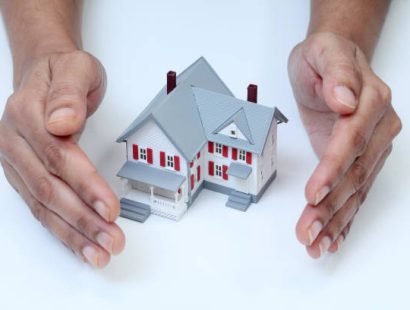 Hands protecting model house on white background